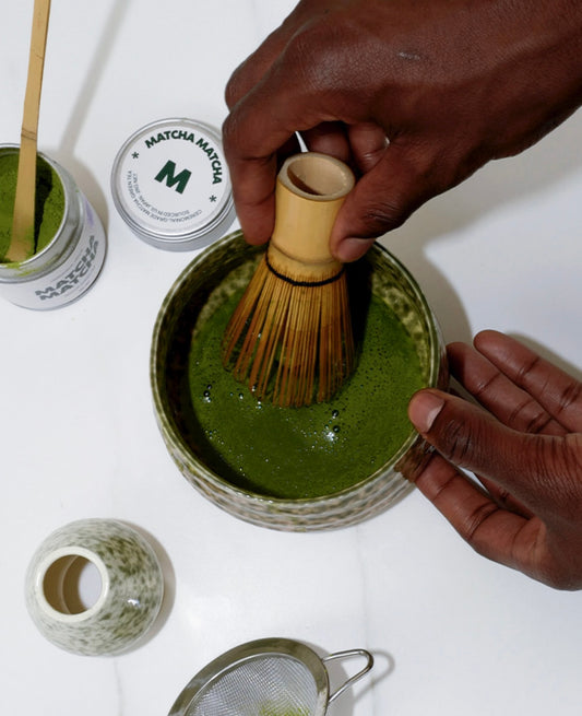 Hand whisking matcha in matcha bowl with bamboo whisk