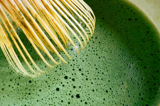 Ceremonial Grade Matcha green tea being whisked with bamboo whisk 